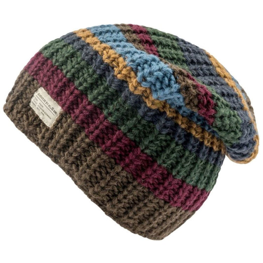A chunky crocheted slouchy beanie hat with horizontal stripes of brown, burgundy, green, blue, and mustard yellow, featuring a white brand label on the side.