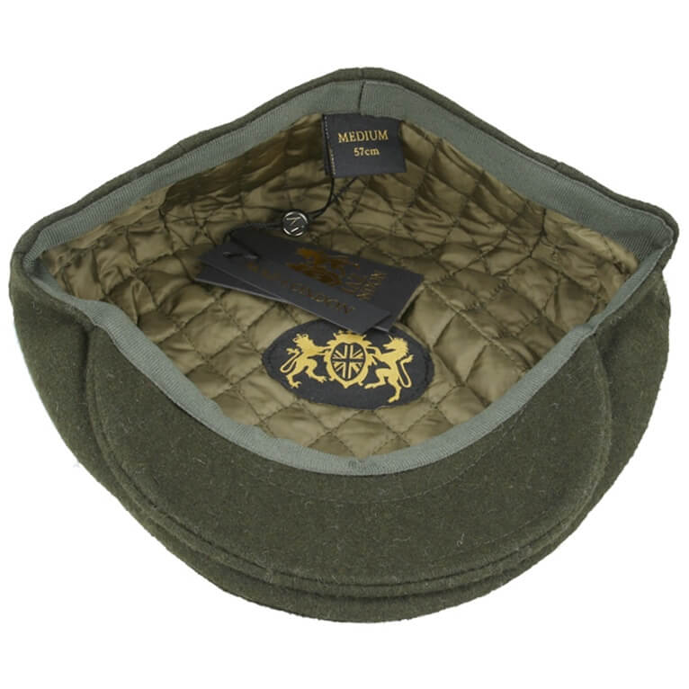 An olive green wool flat cap with a quilted olive green interior lining, featuring a black brand tag, a size label reading 'MEDIUM 57cm', and a gold embroidered crest on the inside.